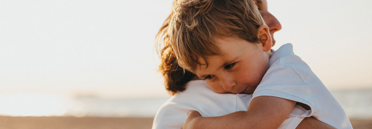 adopted child hugs new mum on beach